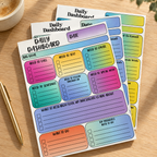 Three colorful Daily Dashboard planning pads in the Classic layout, arranged on a warm wood desk.