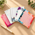 Mini notepad designs on a warm wood desk. One pad per purchase; props not included.